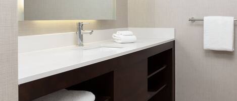 A modern bathroom with a white sink, a mirror, and a towel rack.