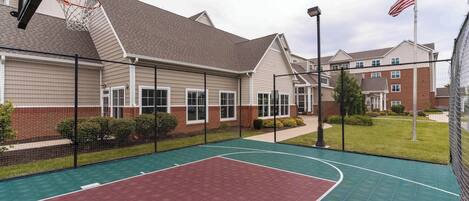 Un terrain de basket en plein air, situé à côté d’un bâtiment et équipé d’un panier de basket.