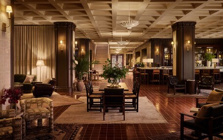 A spacious lobby with a central seating area, a staircase, and a bar/lounge area.