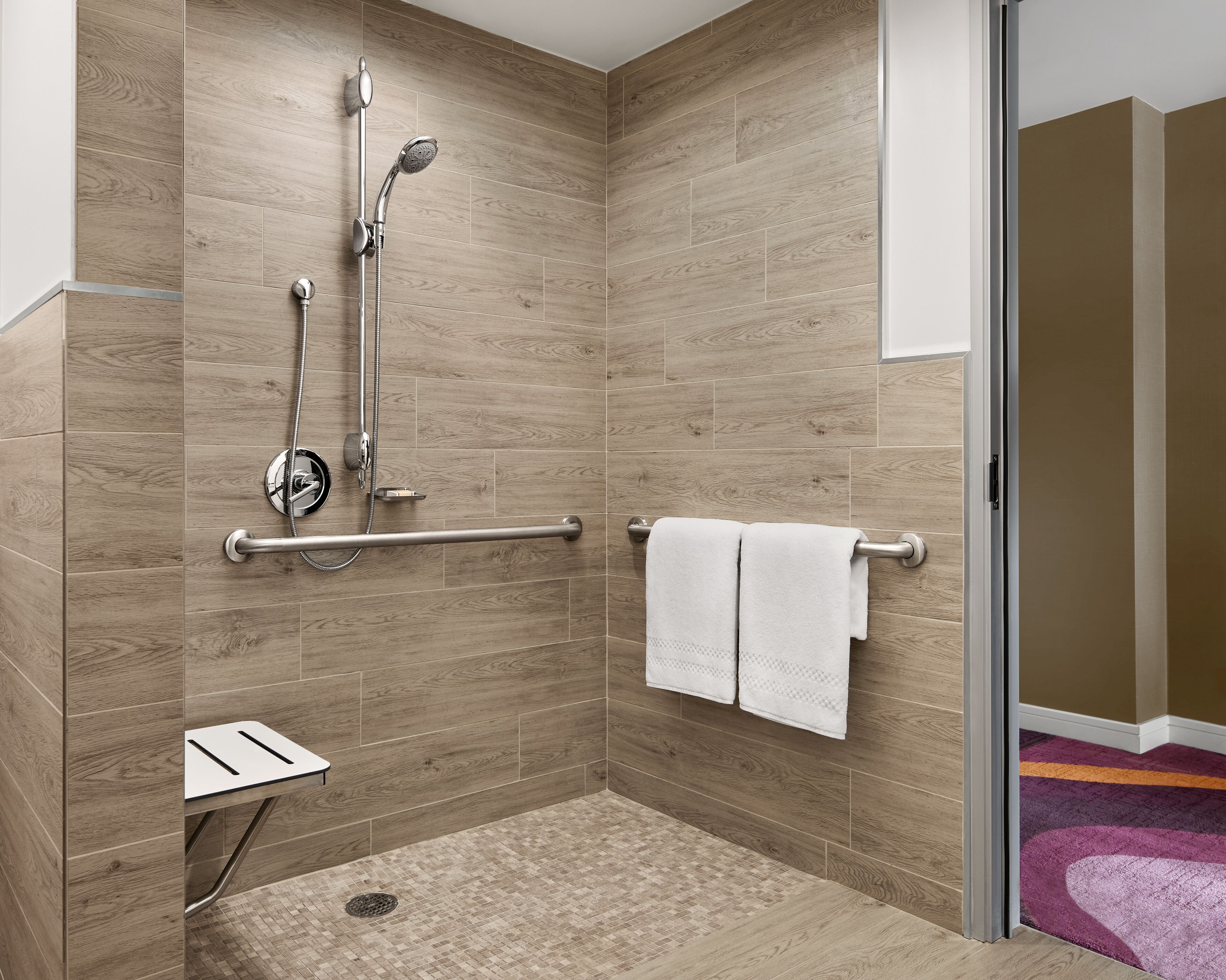 Ein modernes Badezimmer mit Dusche, Haltegriff und Handtuchhalter.