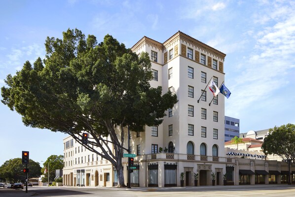 A historic building with a large tree in front, multiple windows, and flags. - Pasadena Hotel & Pool (Pasadena)