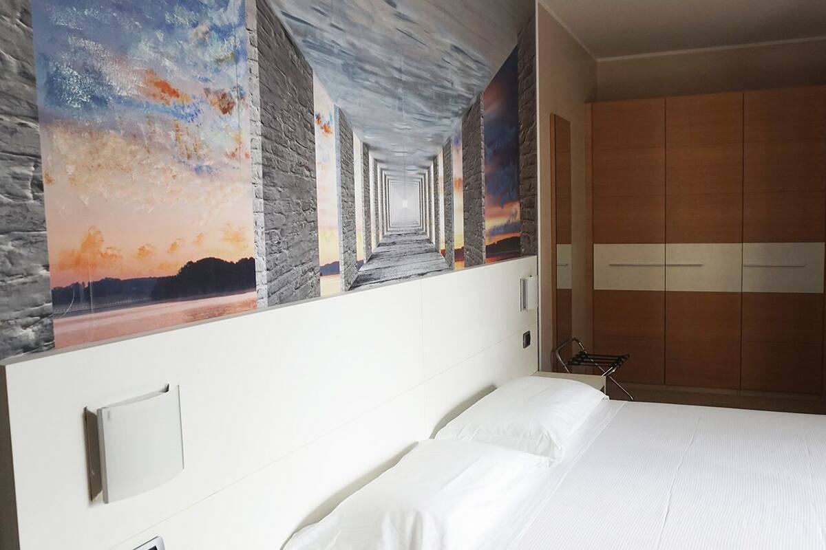 Une chambre d’hôtel avec un grand lit, une armoire et une fresque murale.