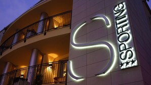 A building with a large illuminated 'S' sign and the words 'SPORTING' on the facade. - Hotel Sporting Brugherio (Brugherio)