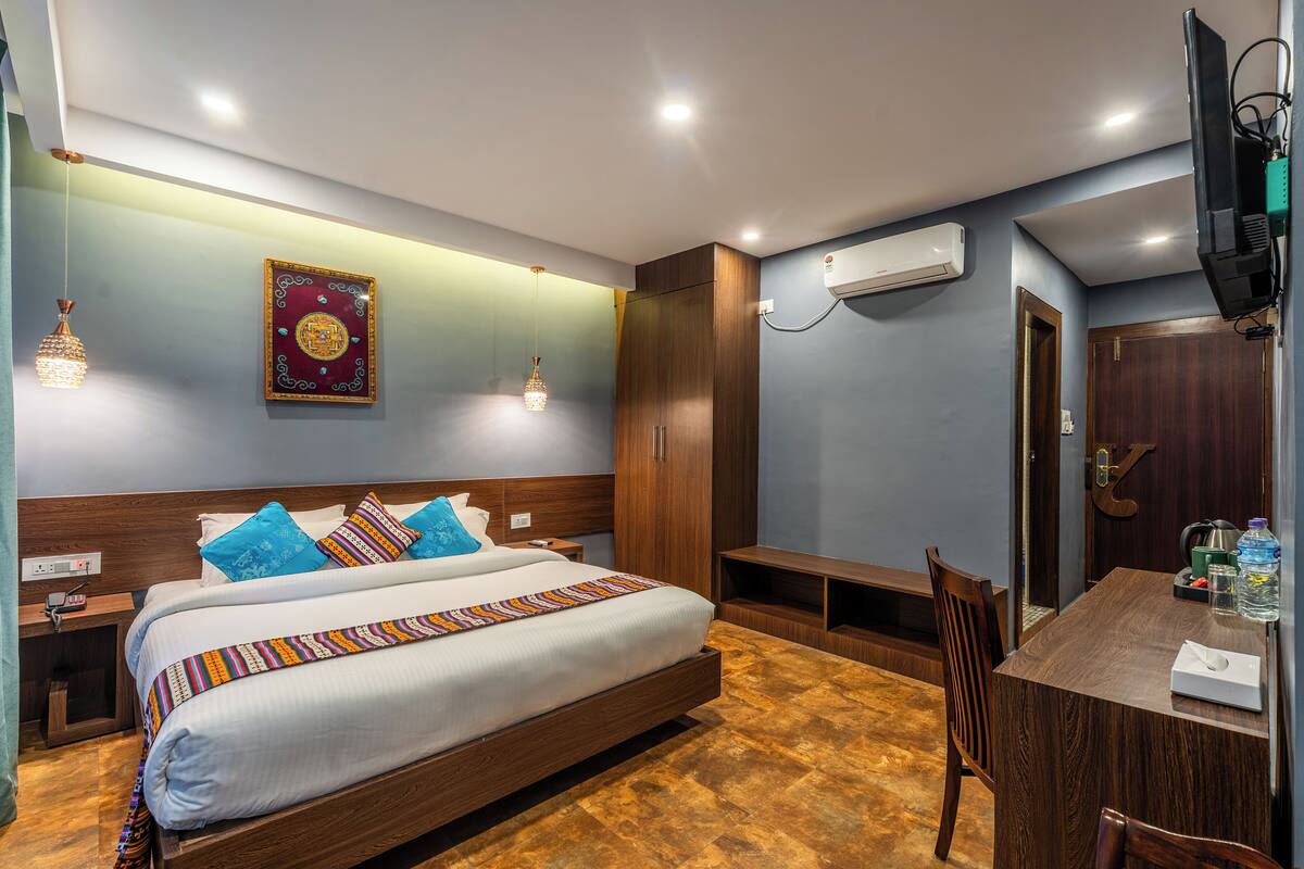 A hotel room with a large bed, wooden headboard, and a desk with a chair.