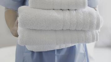 A person in a blue uniform holding a stack of white towels.