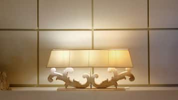 Una lámpara de mesa con pantalla blanca y base de madera con detalles decorativos.