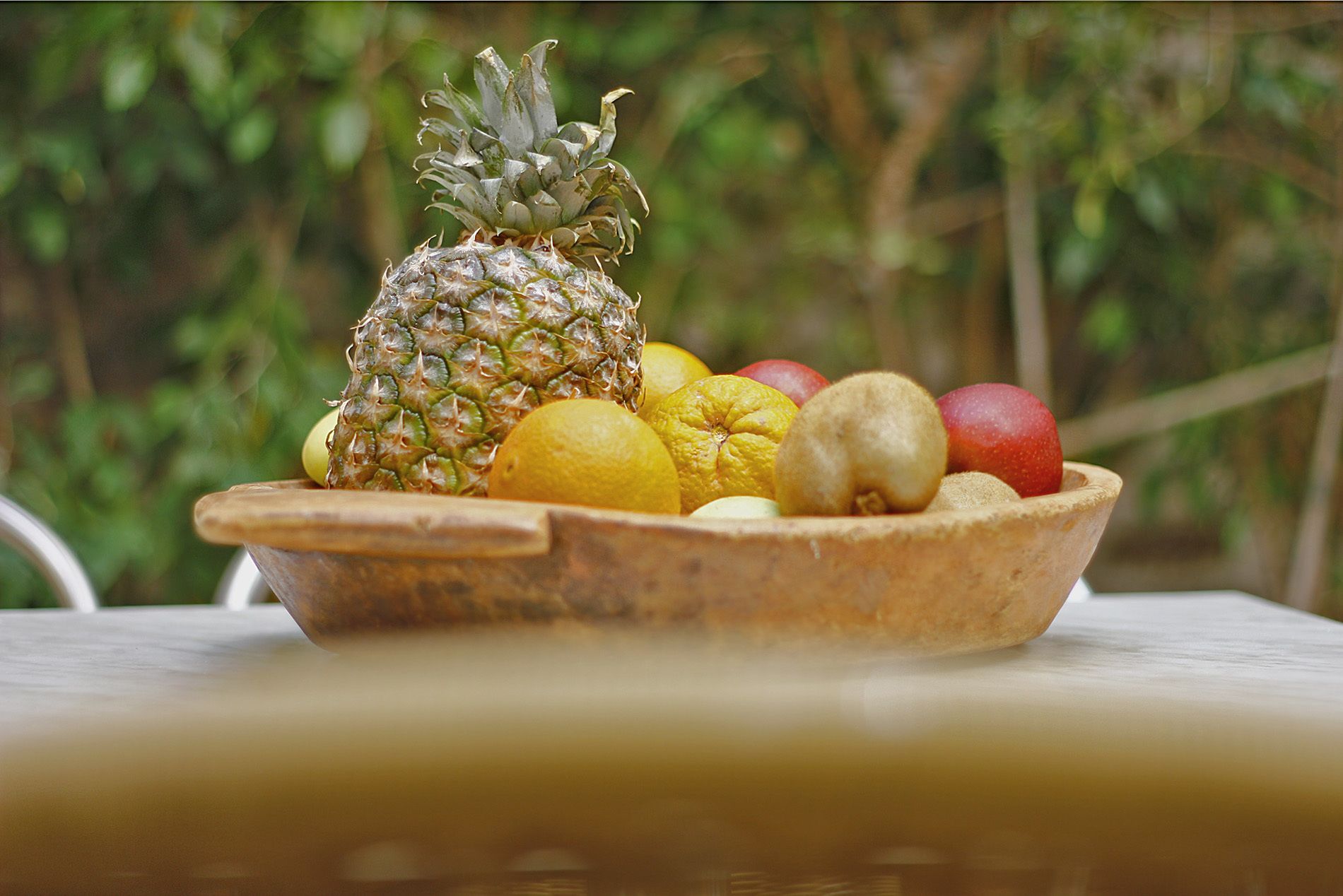 A wooden bowl filled with various fruits on a table.