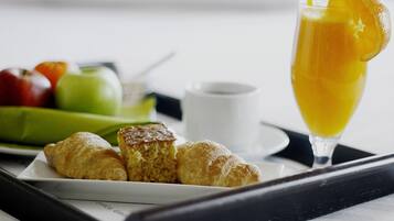 A tray with croissants, a glass of orange juice, and a plate of fruits.