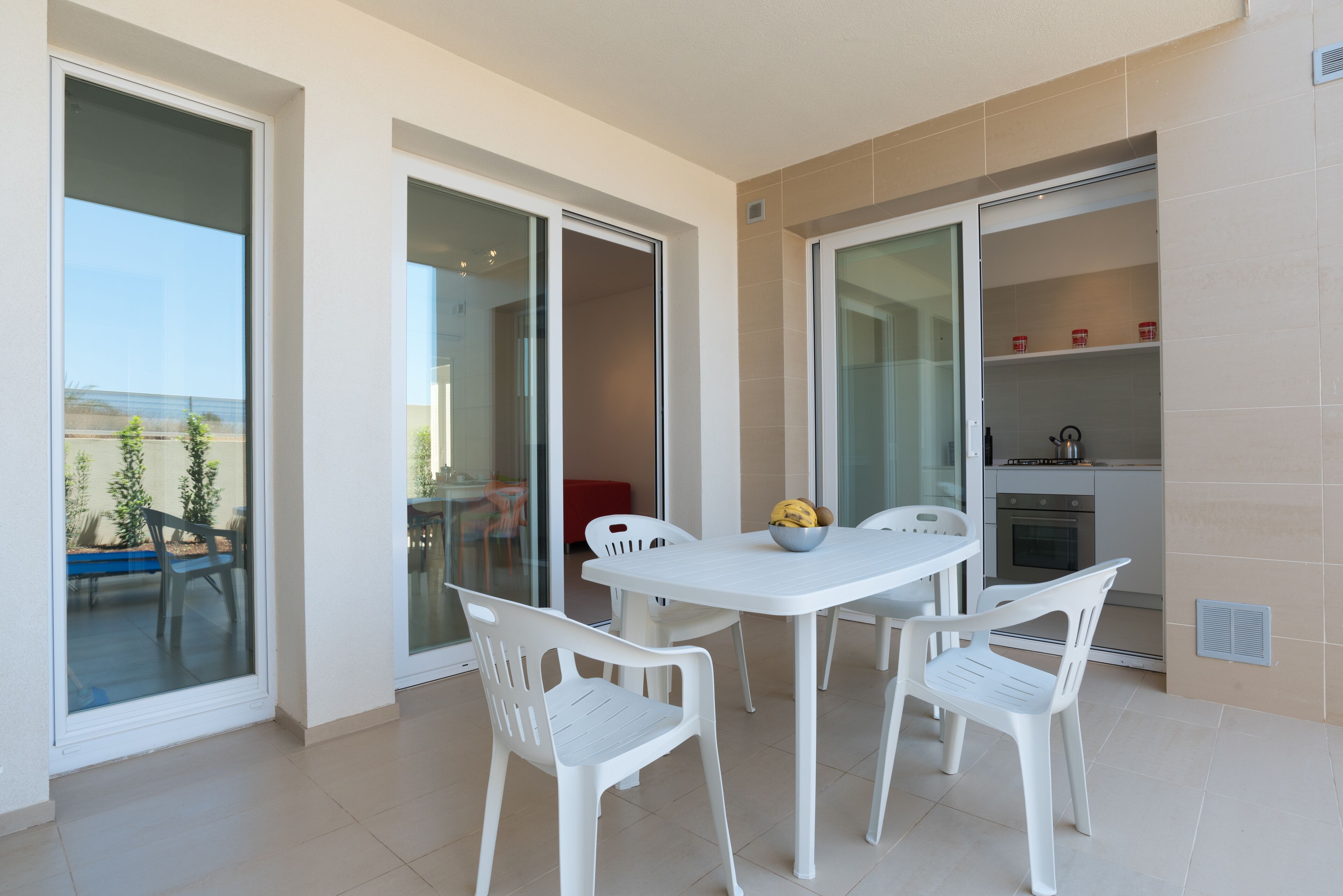 Una cocina moderna con armarios blancos y un comedor con mesa y sillas blancas.
