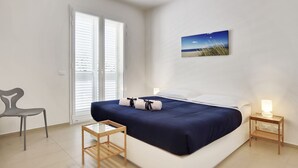 A bedroom with a bed, a nightstand, a chair, and a picture on the wall. - Appartamenti Sud Est (Ragusa)
