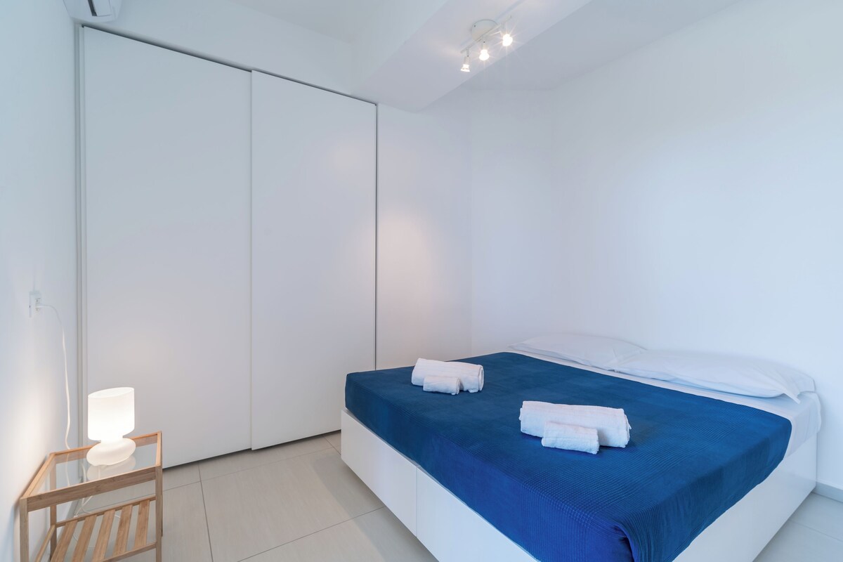 A bedroom with a bed, a bedside table with a lamp, and a wardrobe.