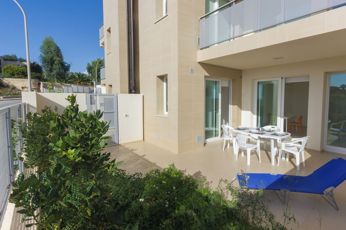 A modern apartment with a balcony, outdoor seating, and a view of the surrounding area.