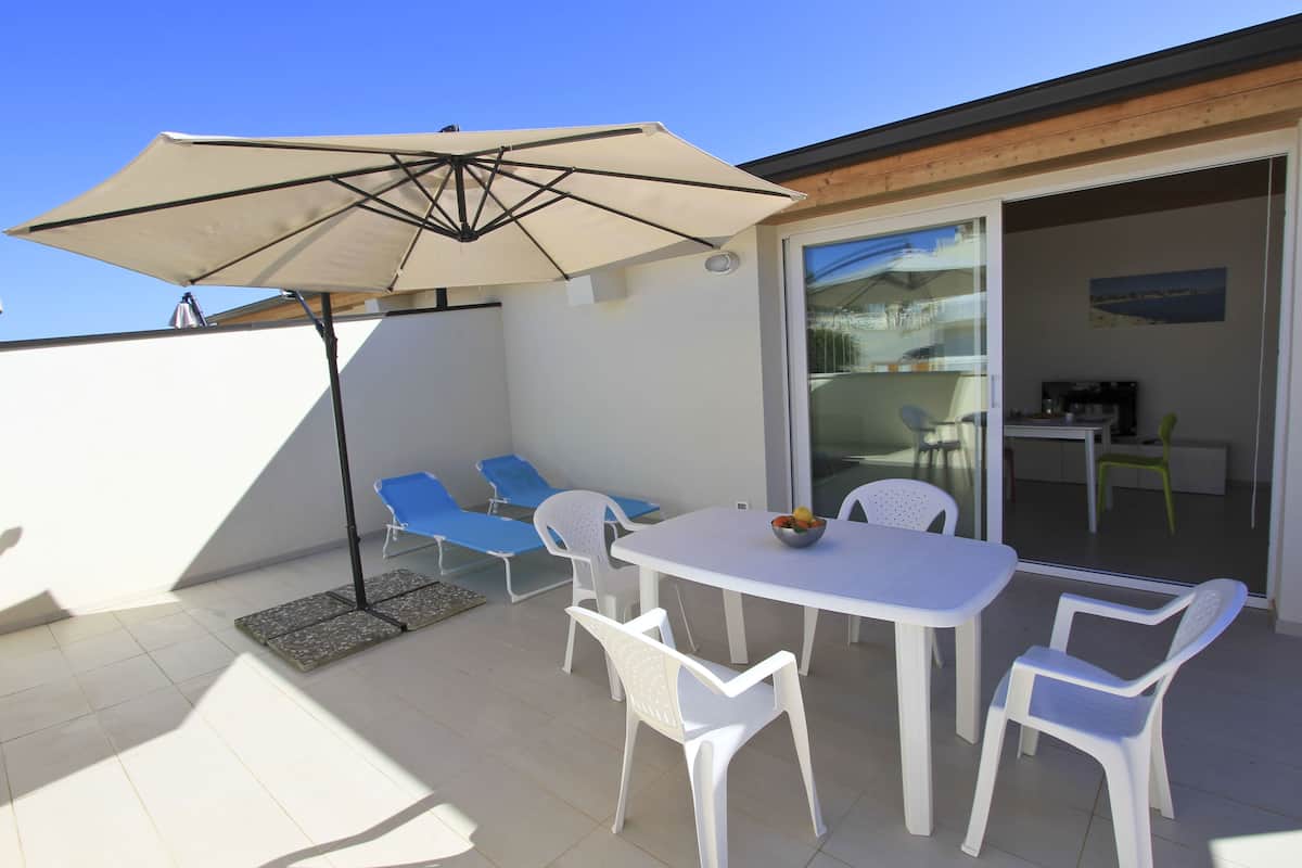A patio with a table, chairs, and an umbrella.