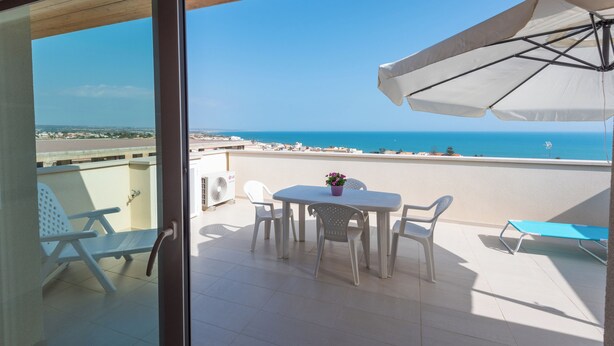 A balcony with a table, chairs, and an umbrella. - Appartamenti Sud Est (Ragusa)