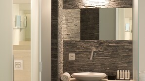 A bathroom with a stone wall, a sink, a mirror, and a towel rack. - Aparthotel Duomo (Milan)