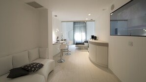 A modern hotel room with a minimalist design, featuring a sofa, a dining area, and a kitchen counter. - Aparthotel Duomo (Milan)