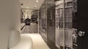 A modern hallway with a white curved bench, a wall mural of a tram, and a door with a dark frame. - Aparthotel Duomo (Milan)