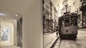 A corridor with a mural of a tram on a track, leading to a room with a large window. - Aparthotel Duomo (Milan)