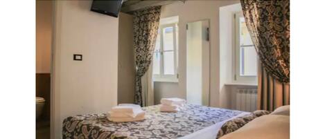 A neatly made bed with a patterned bedspread and two folded towels on it.