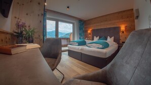 Une chambre à coucher avec un lit, un bureau et une chaise. Il y a une fenêtre qui donne sur les montagnes.