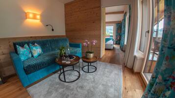 Een moderne woonkamer met een blauwe bank, twee bijzettafels en uitzicht op een balkon.