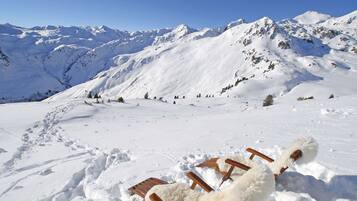 A snow-covered mountain landscape with wooden sleds and fur-covered seats.