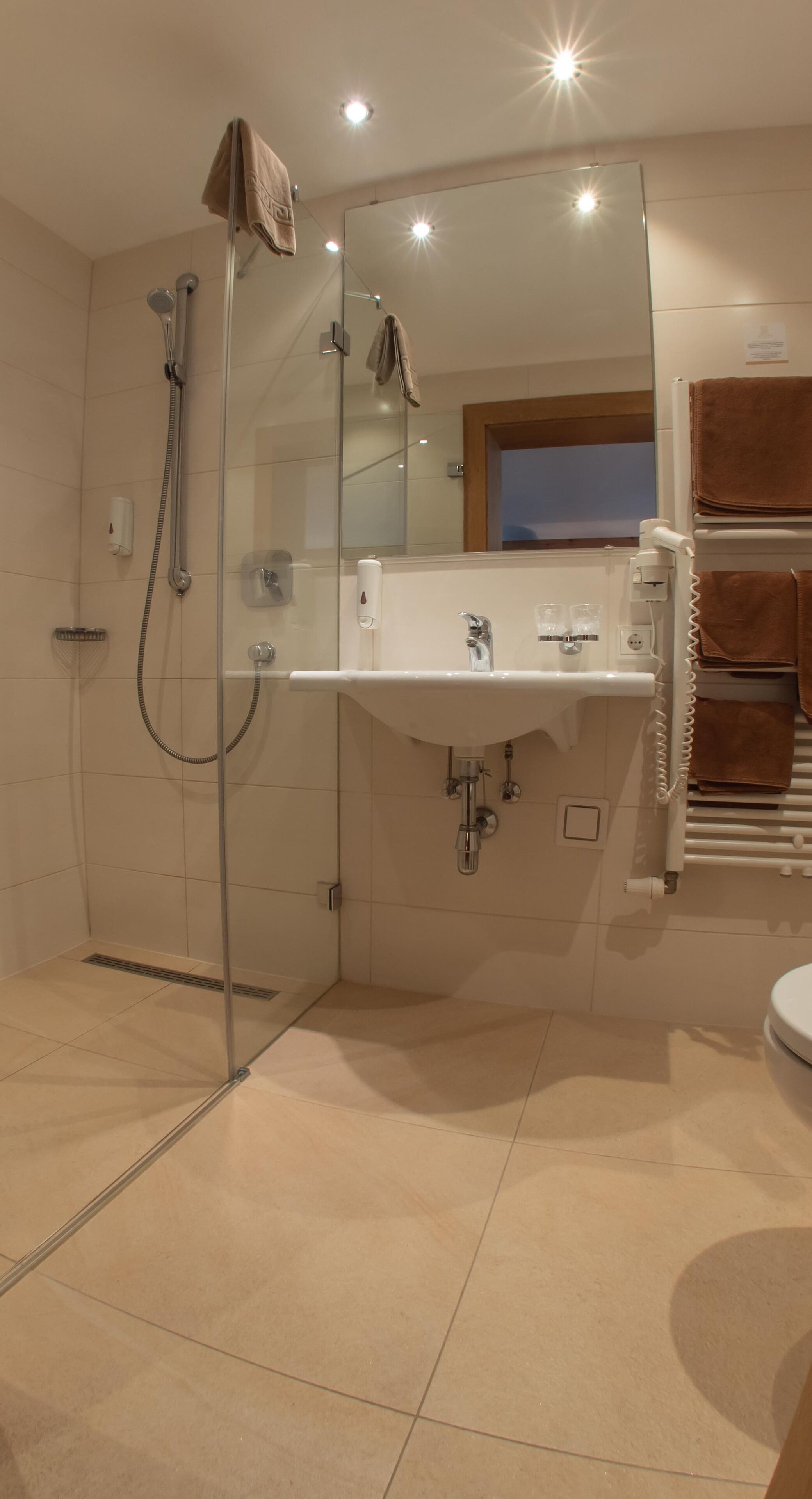 A modern bathroom with a glass-enclosed shower, a white sink, and a large mirror.
