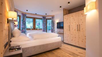 A bedroom with a large bed, wooden wardrobe, and a TV.
