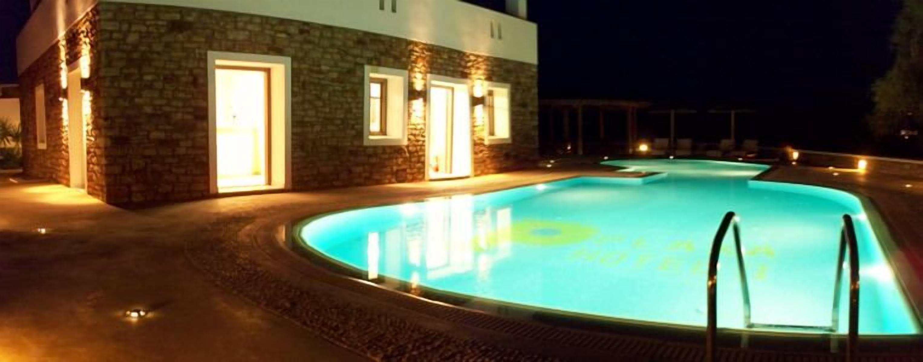 Una piscina con rivestimento in pietra e ingresso ben illuminato.