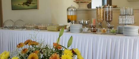 A buffet table with various food items and a floral arrangement in the foreground.