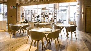 A modern dining area with wooden floors, round tables, and chairs. - Hotel Zenit San Sebastián (San Sebastián)