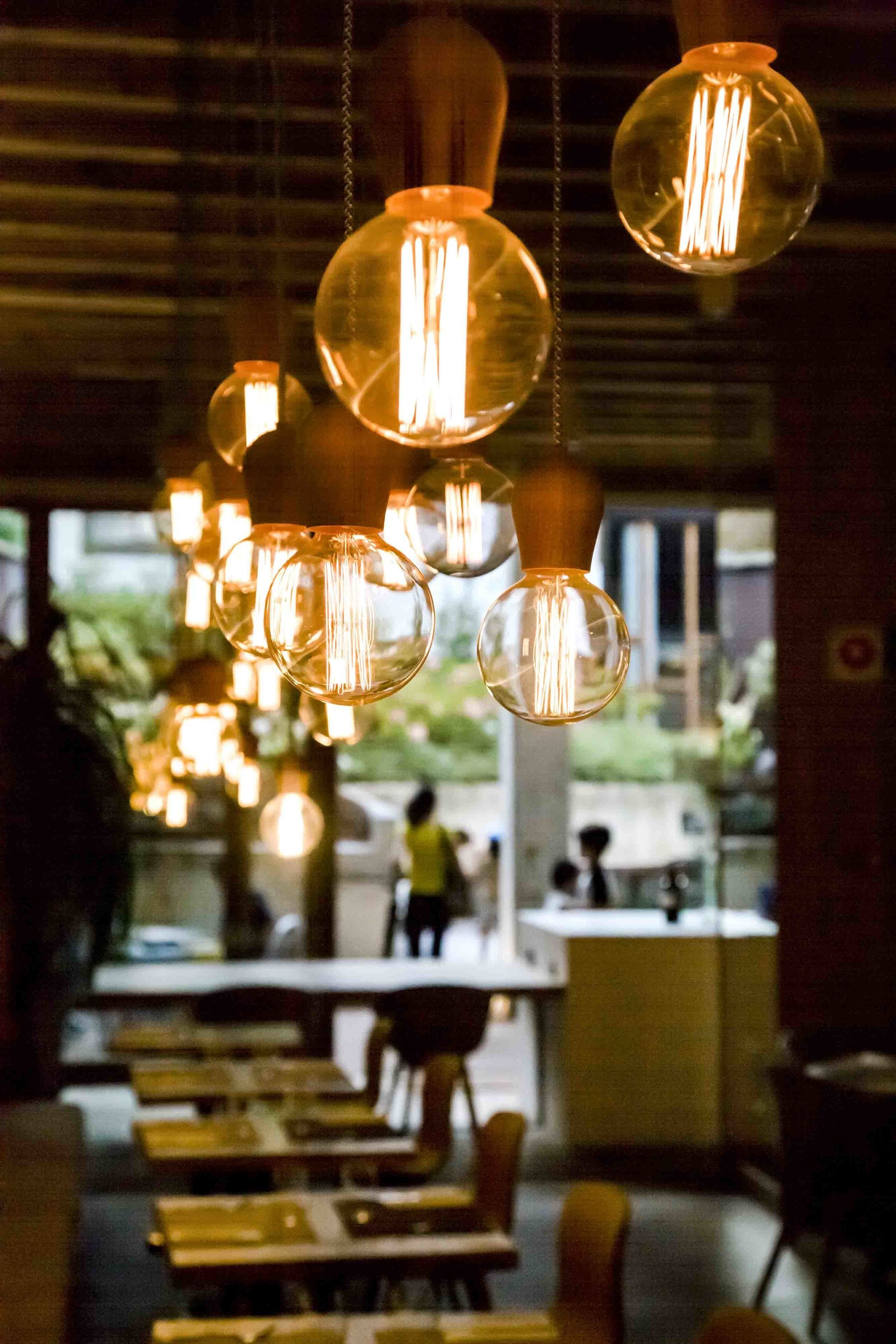 L’intérieur d’un restaurant, avec des luminaires sphériques suspendus et une vue sur la rue.