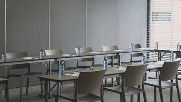 Un salón de conferencias con una larga mesa, varias sillas y botellas de agua sobre la mesa.