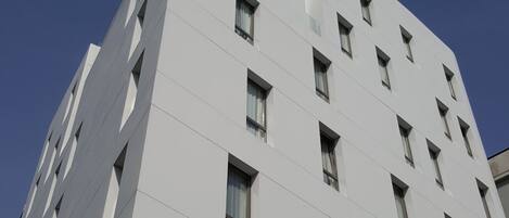 A modern building with a white facade, multiple windows, and a flat roof.