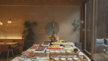 A buffet with various food items, a clock on the wall, and potted plants.
