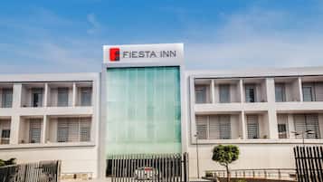 Un edificio moderno con fachada de vidrio y un letrero que dice 'Fiesta Inn'.