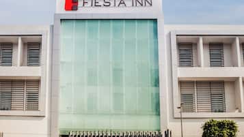 A modern building with a glass facade and a metal gate, labeled "Fiesta Inn."