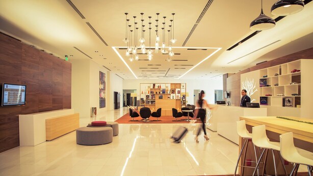 A modern hotel lobby with a reception desk, seating area, and a bar. - Fiesta Inn Plaza Central Aeropuerto (Mexico City)