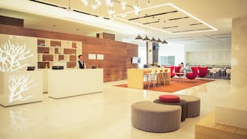 Un moderno vestíbulo de hotel con recepción, zona de estar y un bar.