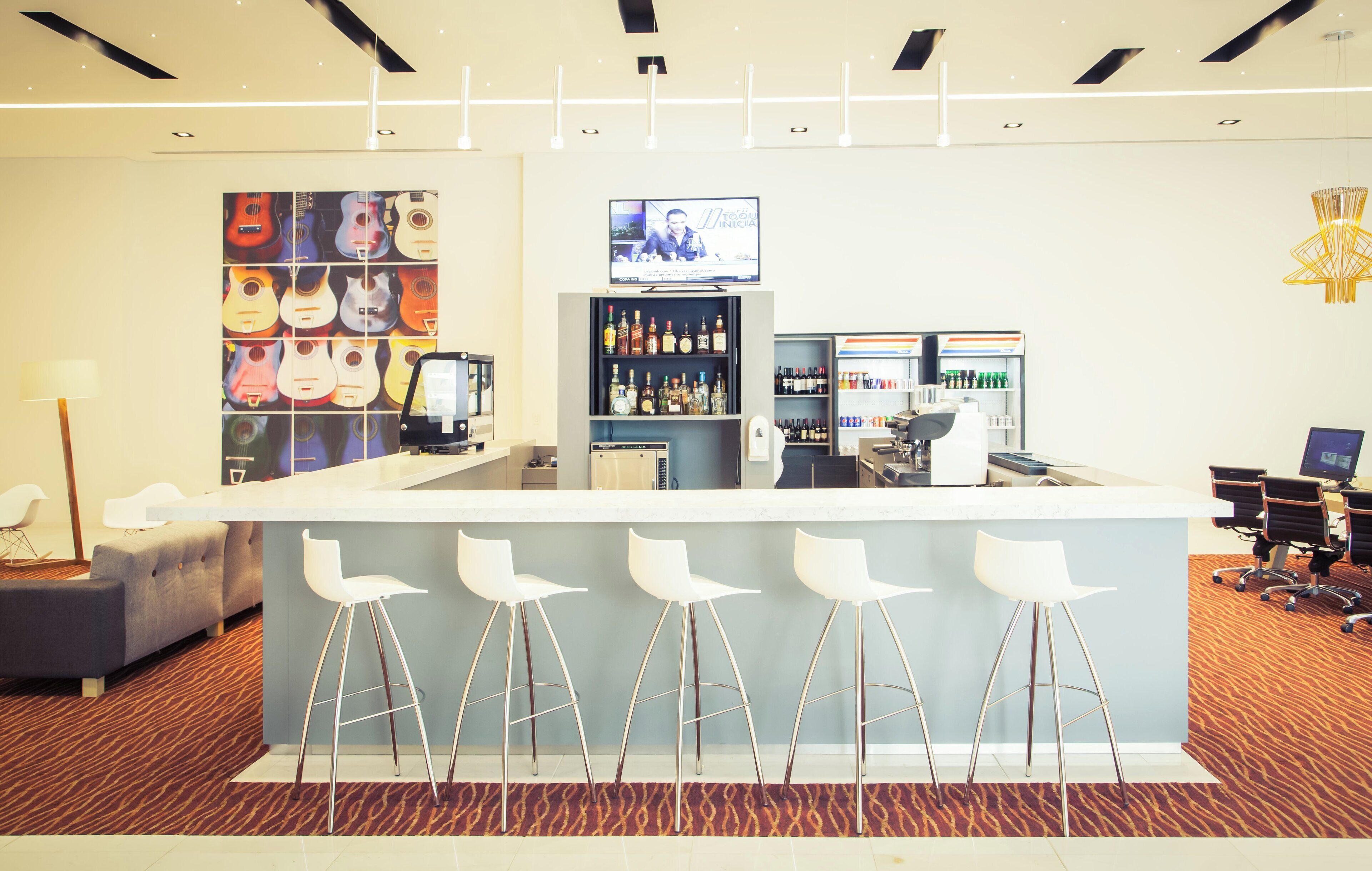 A bar area with a counter, stools, and a television screen.