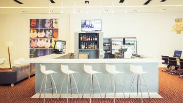 A bar area with a counter, stools, and a television screen.