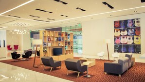 A modern lobby with seating areas, a television, and a bookshelf. - Fiesta Inn Plaza Central Aeropuerto (Mexico City)