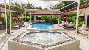 Una piscina al aire libre, sombrillas, sillones reclinables de piscina