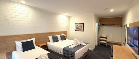 A hotel room with two beds, a desk, a TV, and a framed picture on the wall.