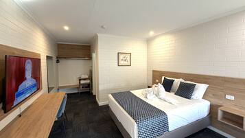 A hotel room with a bed, a TV, a desk, and a wardrobe.