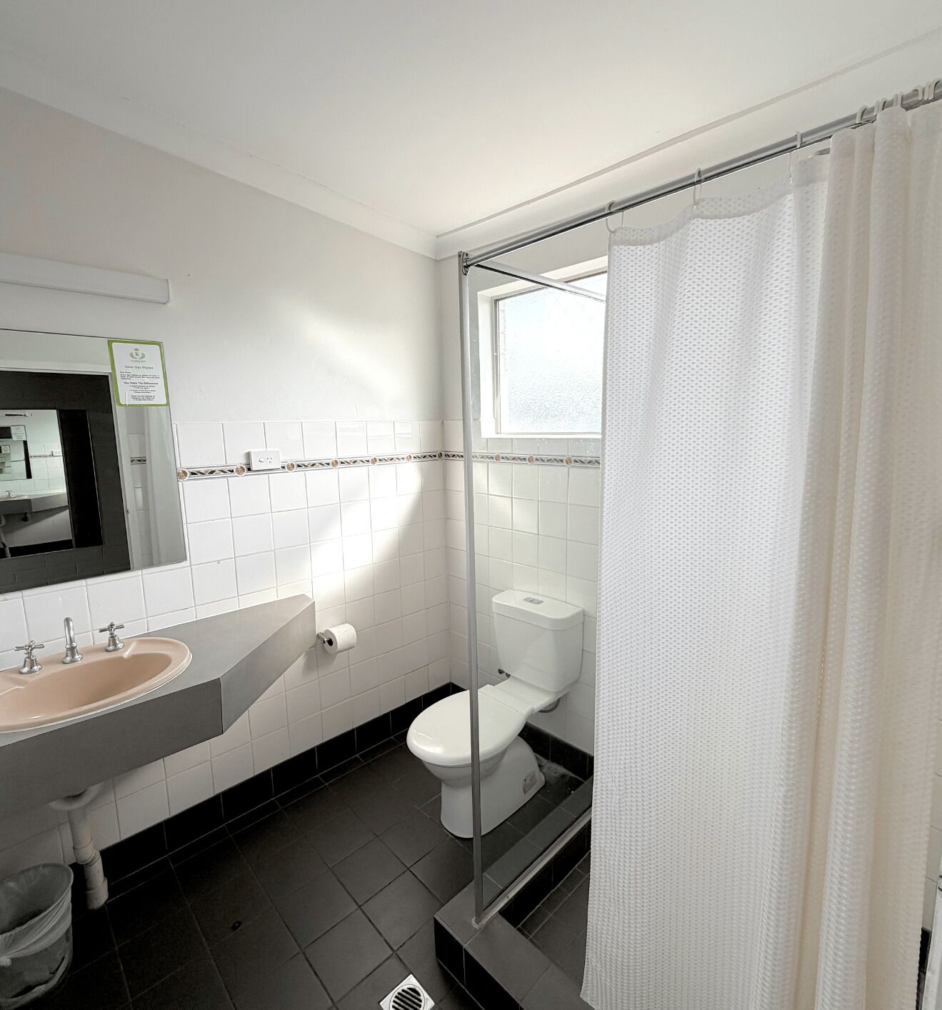 A bathroom with a sink, mirror, toilet, and shower curtain.
