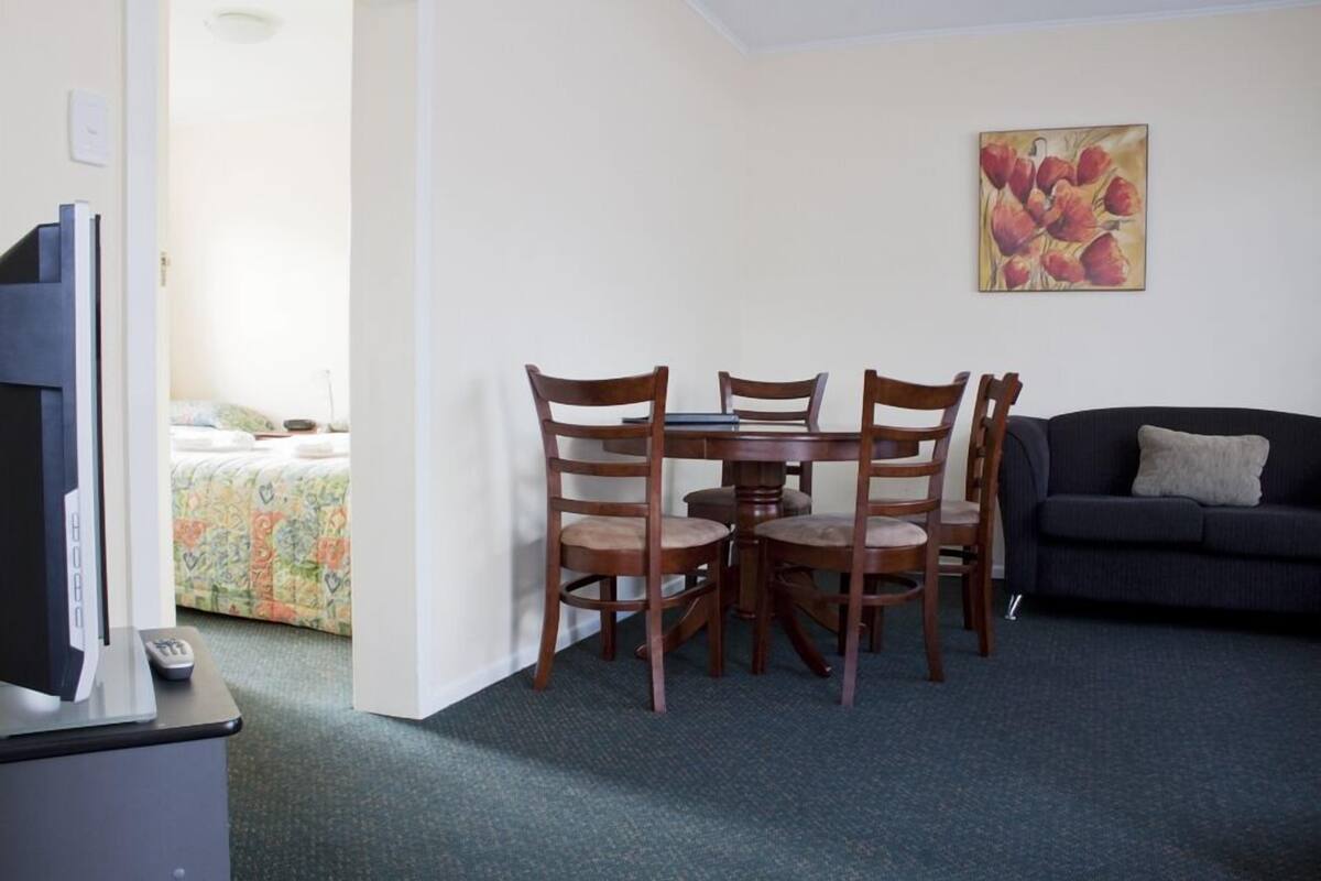 A dining area with a table and chairs, a television, and a sofa.