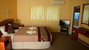 Une chambre d’hôtel avec un lit, une télévision, un bureau et une fenêtre avec des rideaux.