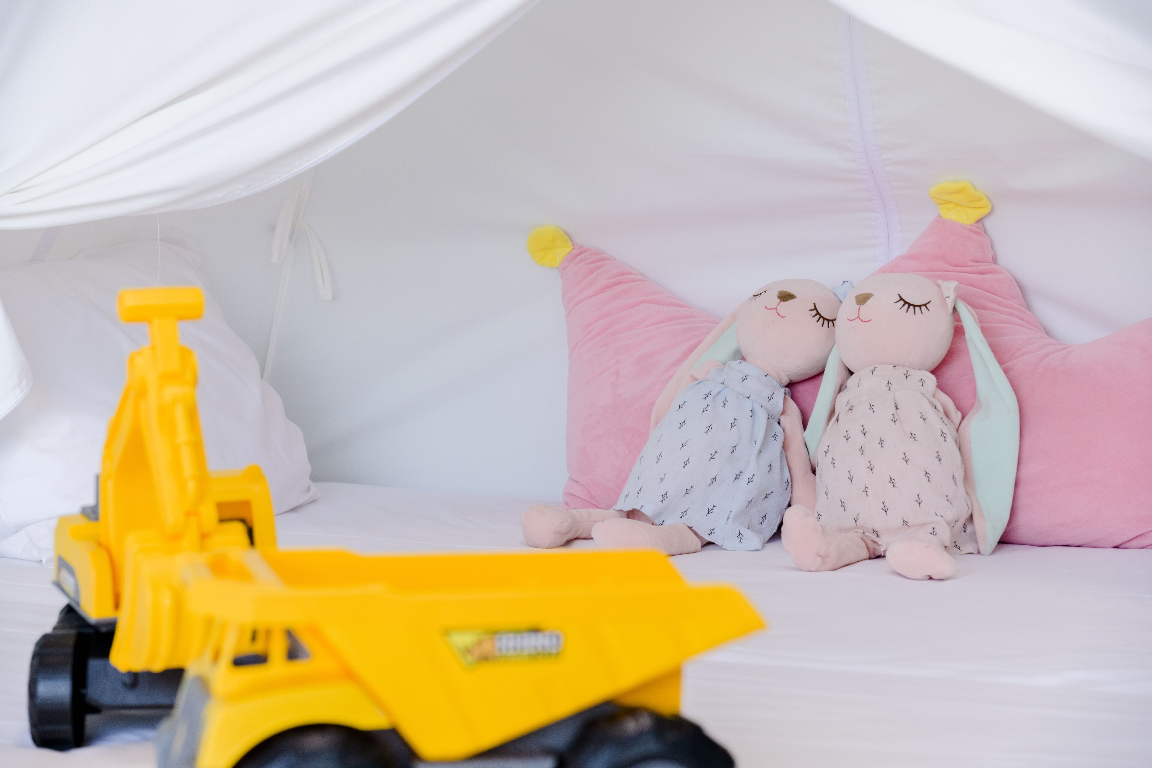 Una cama con peluches y un camión de juguete.