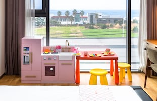 Una habitación con kitchenette, una zona de comedor con taburetes, una cama y vistas a la playa y edificios.
